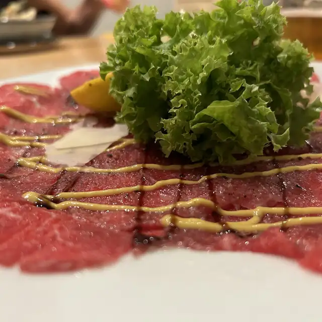 Carpaccio wołowe z sałatą i sosem na białym talerzu